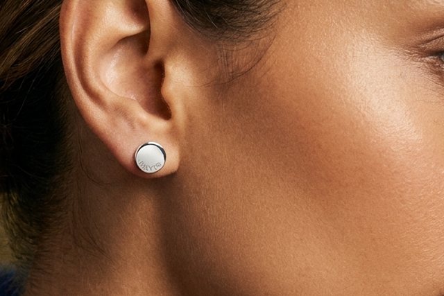 A Hilver silver stud earring worn close up