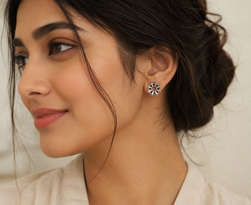 A Hilver handcrafted silver sunburst stud earring, worn close up